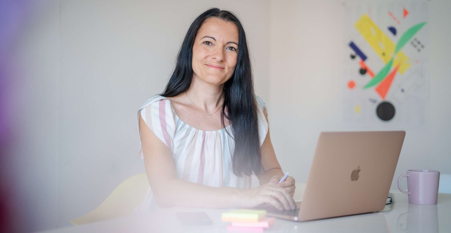 Janett schaut in die Kamera und sitzt vor ihrem Laptop